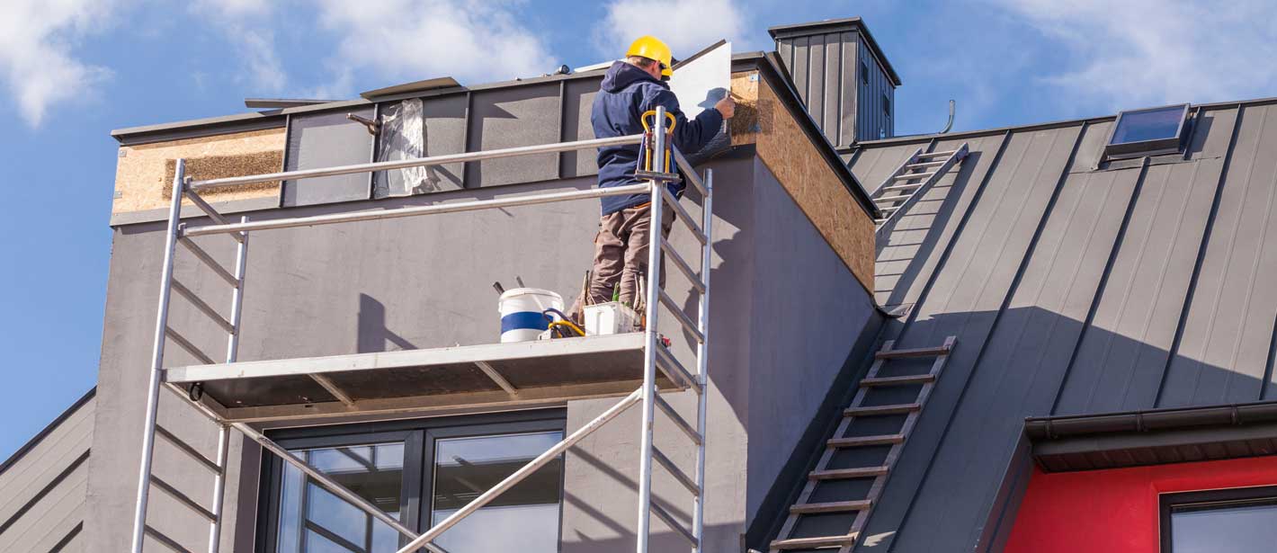 Dachdecker auf Gerüst mit Plan in der Hand